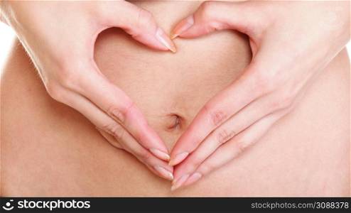 Sexy young woman making heart shape with her hands on her belly