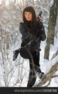 Sexy young woman with a pistol in winter forest