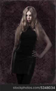 sexy young woman with mystery look and dark dress posing with long blonde hair and creative make-up. Halloween style