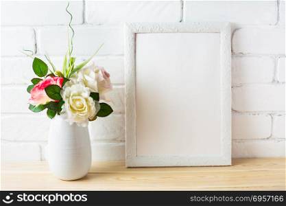 Shabby chic style white frame mockup with pink roses. Shabby chic style white frame mockup with pink roses. Empty white frame mockup for design presentation. Portrait or poster white frame mockup.