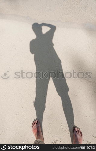 shadow of a photographer on the sand of a tropical beach