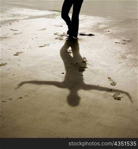 Shadow of a woman standing in the tree pose on the beach