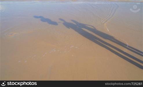 Shadow of couple holding colorful balloons at the beach during travel trip with sand on holidays vacation outdoors at ocean or nature sea at noon, Phuket, Thailand