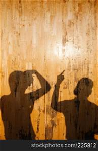 Shadow of Friend couple on yellow pine wood wall with active gesture