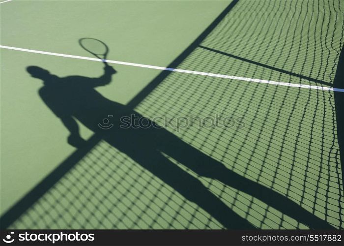 Shadow of senior man playing tennis on court