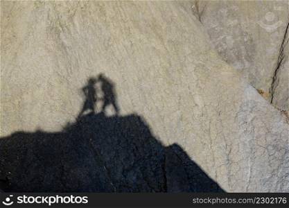 Shadow of two people on rock during hiking in stone mountains. Couple kissing. Happiness and freedom.. Shadow of two people on rock mountain