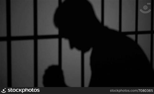 Shadow silhouette of an inmate behind bars