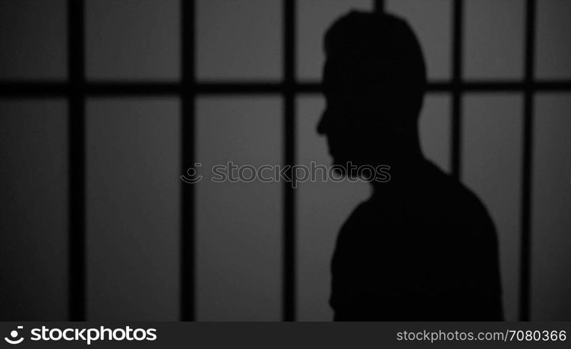 Shadow silhouette of an inmate behind bars