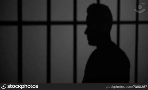 Shadow silhouette of an inmate behind bars