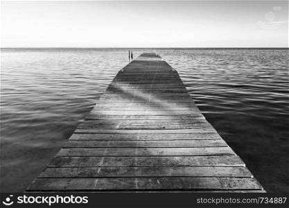 Shadows cut across wooden jetty at sunset in stunning black and white