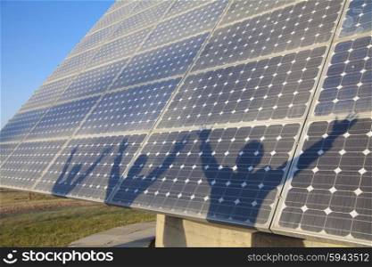 Shadows of Businesspeople with Arms Outstretched on Solar Panel