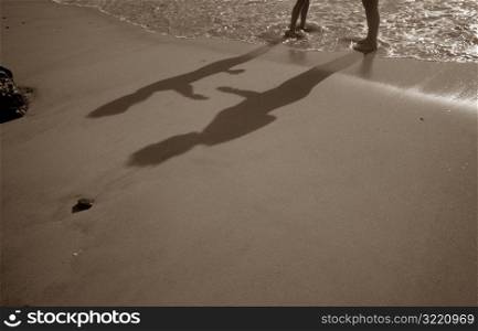 Shadows Of Father And Son Playing On Beach