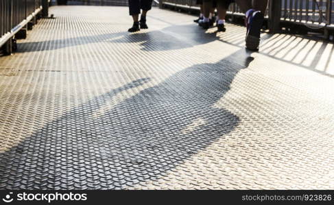 Shadows of people walking on the steel overpass