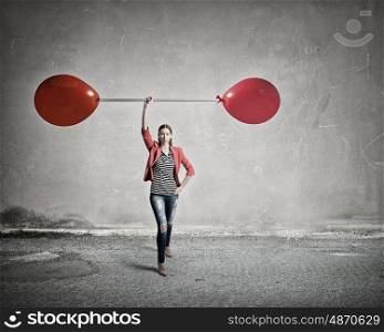 Shae is powerful and determined. Young woman in red jacket lifting barbell in one hand