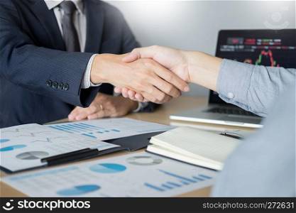 shaking Hand between businessman of cooperation over Stock market chart, business trading concept