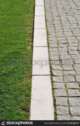 shallow depth of field on green grass and stone calcada pavement as a business concept (soft versus rough)