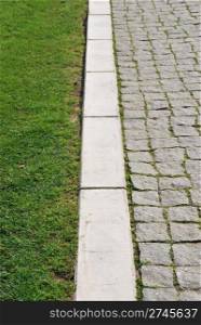 shallow depth of field on green grass and stone calcada pavement as a business concept (soft versus rough)