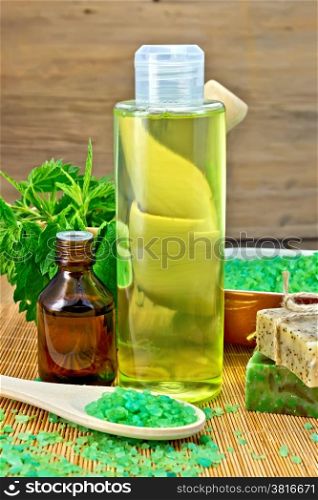 Shampoo, oil, gel, salt, soap with nettles in a mortar on a wooden boards background
