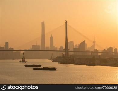 SHANGHAI, CHINA - OCTOBER 27, 2018   Huangpu river in Shanghai towards Yangpu bridge at sunset. Yangpu suspension bridge across river Huangpu in Shanghai