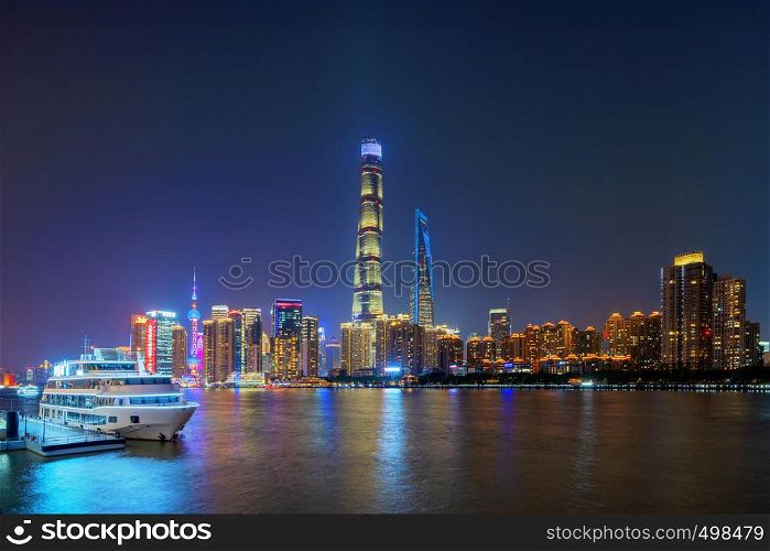 Shanghai Downtown with a boat and Huangpu River, China. Financial district and business centers in smart city in Asia. Top view of skyscraper and high-rise buildings at night.