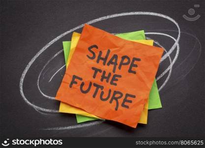 shape the future - motivational slogan on sticky notes against black paper with white chalk drawing
