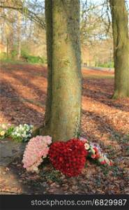 Shaped sympathy or funeral flowers near a tree at a cemetery