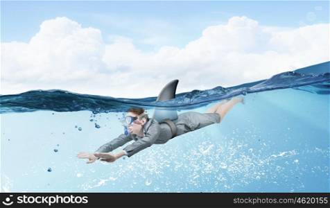 Shark of business world. Young businesswoman with shark flipper swiming under water