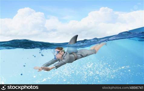 Shark of business world. Young businesswoman with shark flipper swiming under water