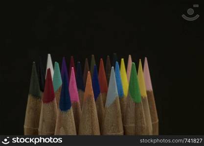 sharp colored pencils on a black background. copy space