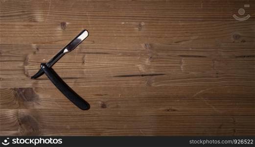 sharp open straight razor lying on a rough wooden background. old straight razor