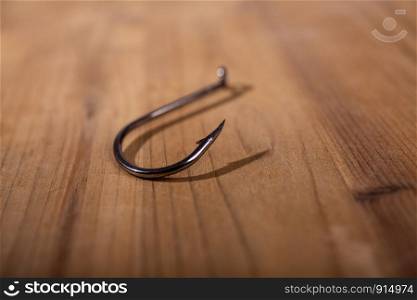 sharp steel big empty fishing hook on a wooden surface. iron fishing hook