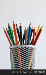 Sharpened colored pencils in pencil holder, on white background.