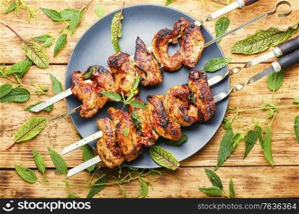Shashlik with nettle marinade.Meat on skewers,barbecue.Shish kebab on wooden background. Shish kebab or BBQ meat