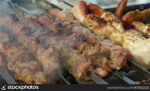 shashlyk of pork and chicken wings being prepared on a mangal, closeup