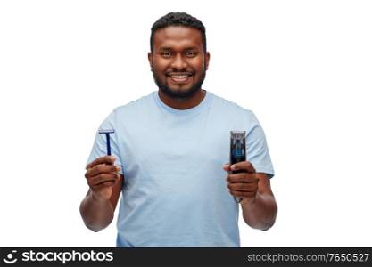 shaving, grooming and people concept - smiling young african american man choosing between manual razor blade and trimmer over white background. smiling african man with razor blade and trimmer