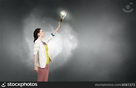 She has bright idea. Businesswoman reaching hand to touch glass glowing light bulb