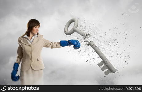 She is absolute winner. Young businesswoman in blue boxing gloves breaking stone key