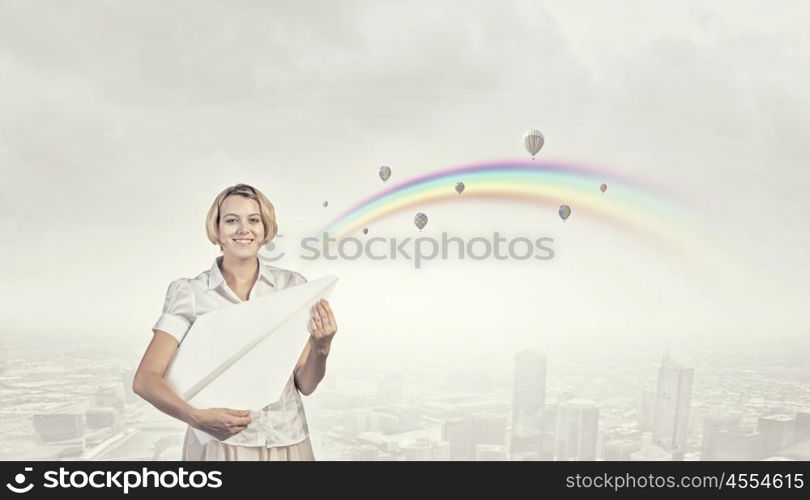 She is acting like child. Young carefree woman with paper plane in hands