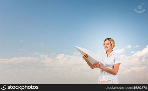 She is acting like child. Young carefree woman with paper plane in hands