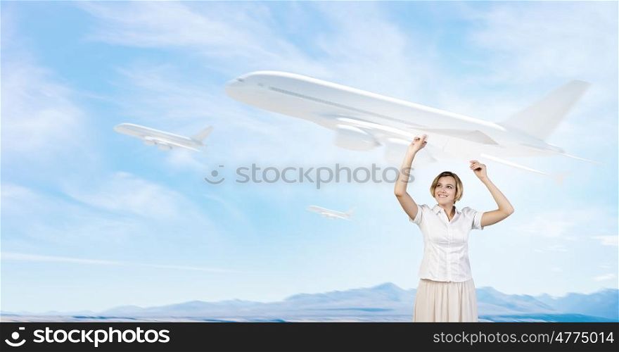 She is acting like child. Young carefree woman with paper plane in hands