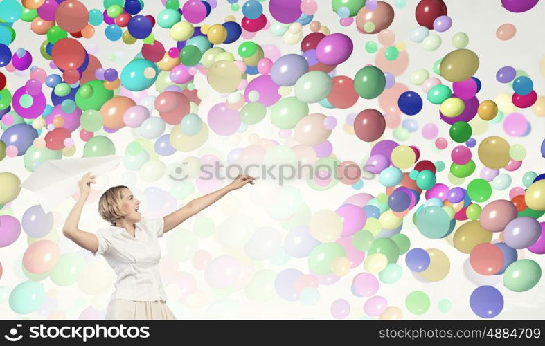 She is acting like child. Young carefree woman with paper plane in hands