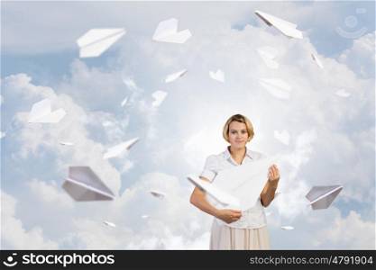 She is adult but still feeling playful . Young cheerful pretty woman playing with paper plane
