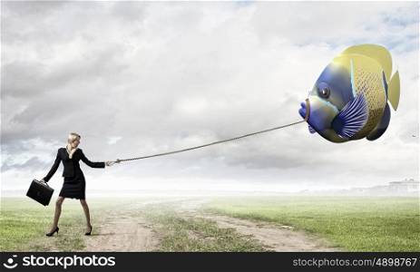 She is big fish in business. Young businesswoman walking with big exotic fish on lead