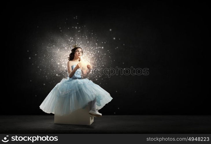 She is cute princess. Little girl princess in blue dress with diadem on head and red heart in hands