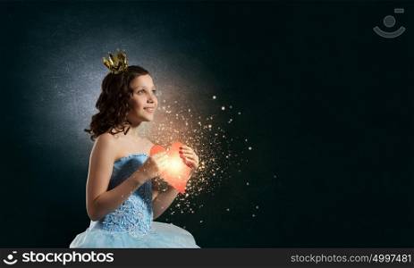 She is cute princess. Little girl princess in blue dress with diadem on head and red heart in hands