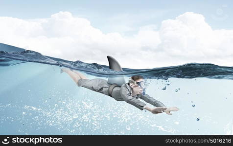 She is dangerous like shark. Young businesswoman with shark flipper swiming under water