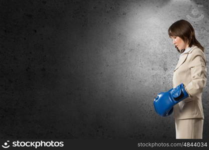 She is fighter. Young businesswoman in blue boxing gloves competition ready