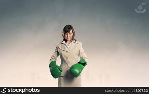 She is fighter. Young businesswoman in green boxing gloves competition ready