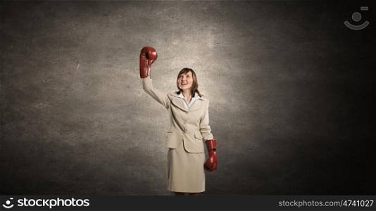 She is fighter. Young businesswoman in red boxing gloves competition ready