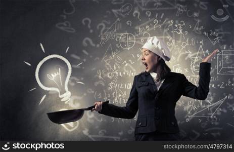 She is going to cook her idea. Pretty businesswoman in suit and cook hat with pan in hand